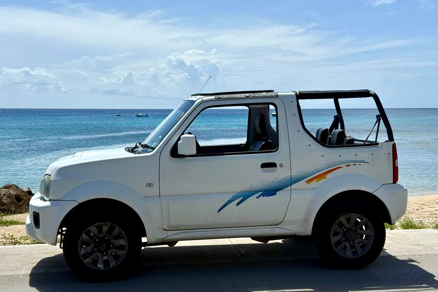 Suzuki Jimny rental in Barbados shown in coastal side profile beside the water