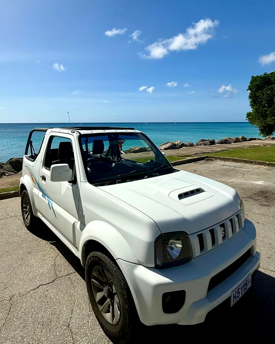 Suzuki Jimny rental parked beside the Barbados waterfront on a scenic coastal drive